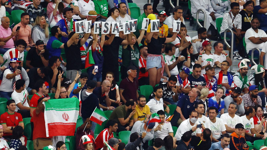দ্বিতীয়ার্ধের শুরুতে কিছুটা সময় কয়েকজন দর্শক মাহসা আমিনির নাম লেখা ব্যানার তুলে ধরেন। ছবি: রয়টার্স
