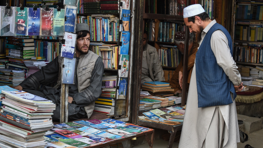 কাবুলের বাজারে ক্রেতার সঙ্গে কথা বলছেন এক বই বিক্রেতা। ছবি: এএফপি