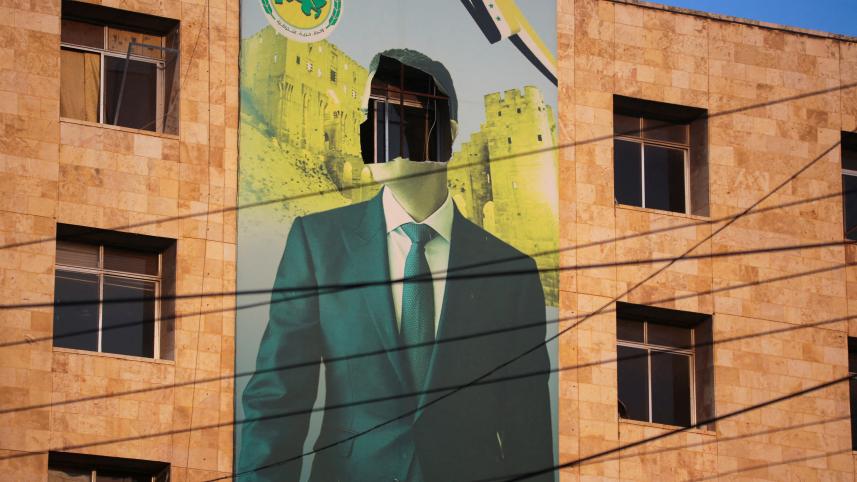 সিরিয়ার আলেপ্পো শহরের দখল নেওয়ার পর একটি পোস্টার থেকে প্রেসিডেন্ট বাশার আল-আসাদের মুখ মুছে দেয় বিদ্রোহীরা। ছবি: রয়টার্স 