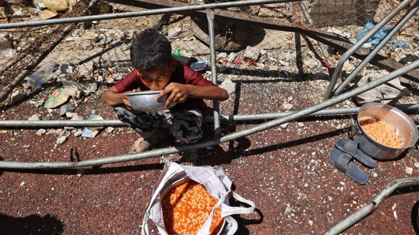নুসেইরাত শিবিরে খাবার খাচ্ছে এক অভুক্ত ফিলিস্তিনি শিশু। ছবি: এএফপি