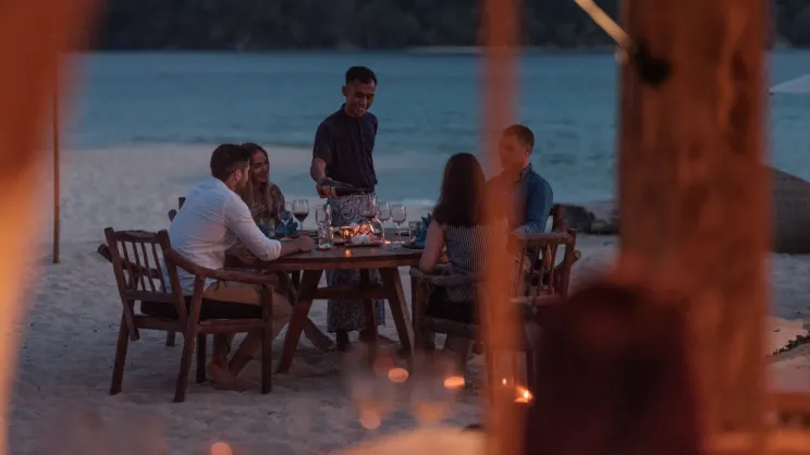 male-staff-pouring-wine-for-couples-in-boat-house-sanggah-background