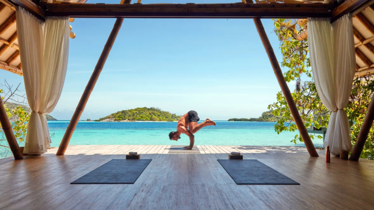 young-man-doing-yoga-crow-pose-under-the-sun-at-aura-wellbeing-deck