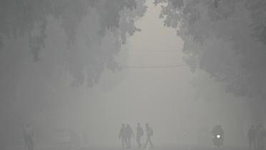 বিষাক্ত ধোঁয়াশার চাদরে ঢাকা নয়াদিল্লিতে পথচারীরা হেঁটে বেড়াচ্ছেন। ছবি: এএফপি