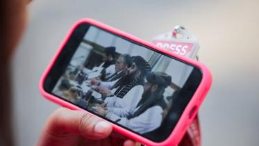 এক নারী সাংবাদিক তার মোবাইলে আফগান পররাষ্ট্রমন্ত্রীর সঙ্গে ভারতের পররাষ্ট্রমন্ত্রীর বৈঠকের লাইভ দেখছেন। বৈঠকে কোনো নারী সাংবাদিক প্রবেশের অনুমতি পাননি। ছবি: রয়টার্স